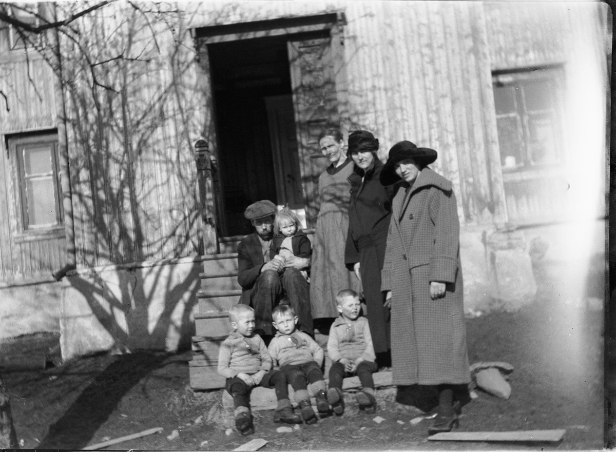 Ole M Martinsen, Ukjent gruppe kvinner, en mann med et barn på fanget, og tre gutter på trappa til inngangen til et hus.