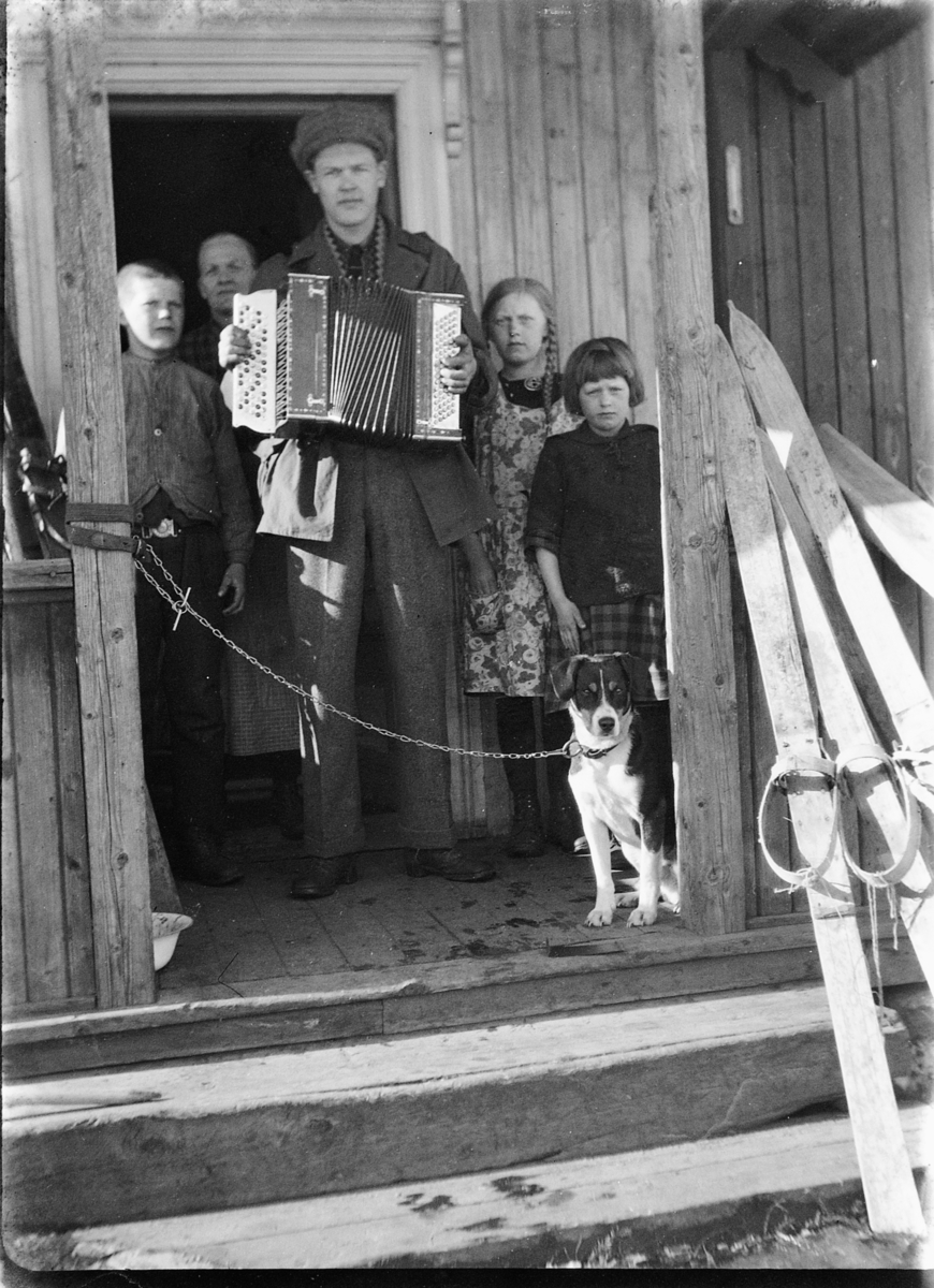 Ole M Martinsen, Trekkspill og ski. Ukjente personer med en hund på trappa til et hus.