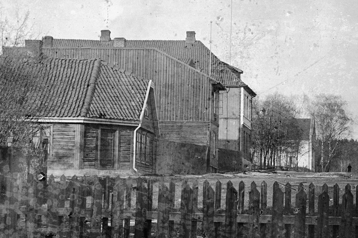 Hans Emil Erichsen, Heidmannsgate, Skappels gate i Hamar med bebyggelse. Stakittgjerde i forgrunnen. Utsnitt.