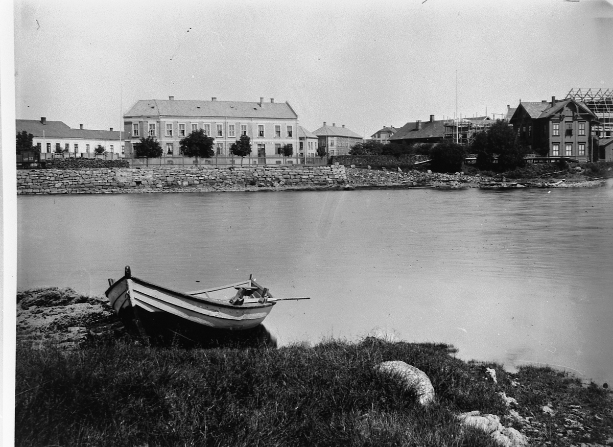 Hans Emil Erichsen, Jernbanehotellet i midten, den gamle Hamar Jernbanestasjon til høyre. Helt til venstre er Wieberggården der Sparebanken Hedmark ligger i dag, og man kan se Grand Hotell under oppføring helt til høyre. Robåt i forgrunnen.
