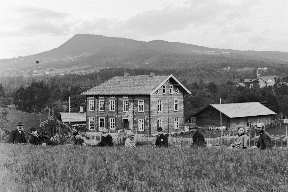 Hans Emil Erichsen, Forretningsgården Finsal i Brumunddal. Kjøpmann Sørlie bygde gården i 1886. Ble overtatt av K. Kolloen før 1900. Senere kjent som Kolloengården. Til høyre i bakgrunnen er Brumunddal Brenneri. Personene på bildet fra venstre Jens Buttekvern f. ca. 1840, student Andreas Erichsen f. 1874, stud. theol.…