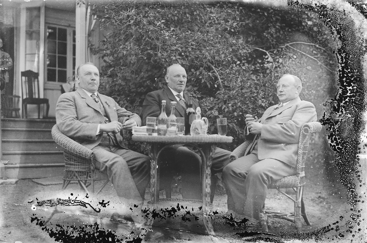 Oscar Løberg, Tre menn samlet rundt et bord med drikke i en hage.
