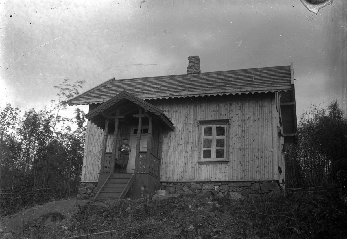 Kristian Heramb, En gutt, med en katt i armene, på veranda til et hus.