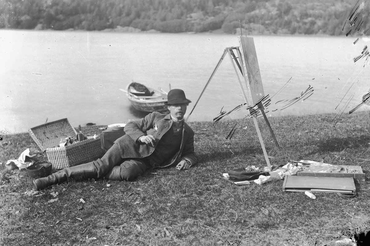 Hans Emil Erichsen, Kunstmaler Ludvig Skramstad med staffeli og malersaker i strandkanten. Robåt.