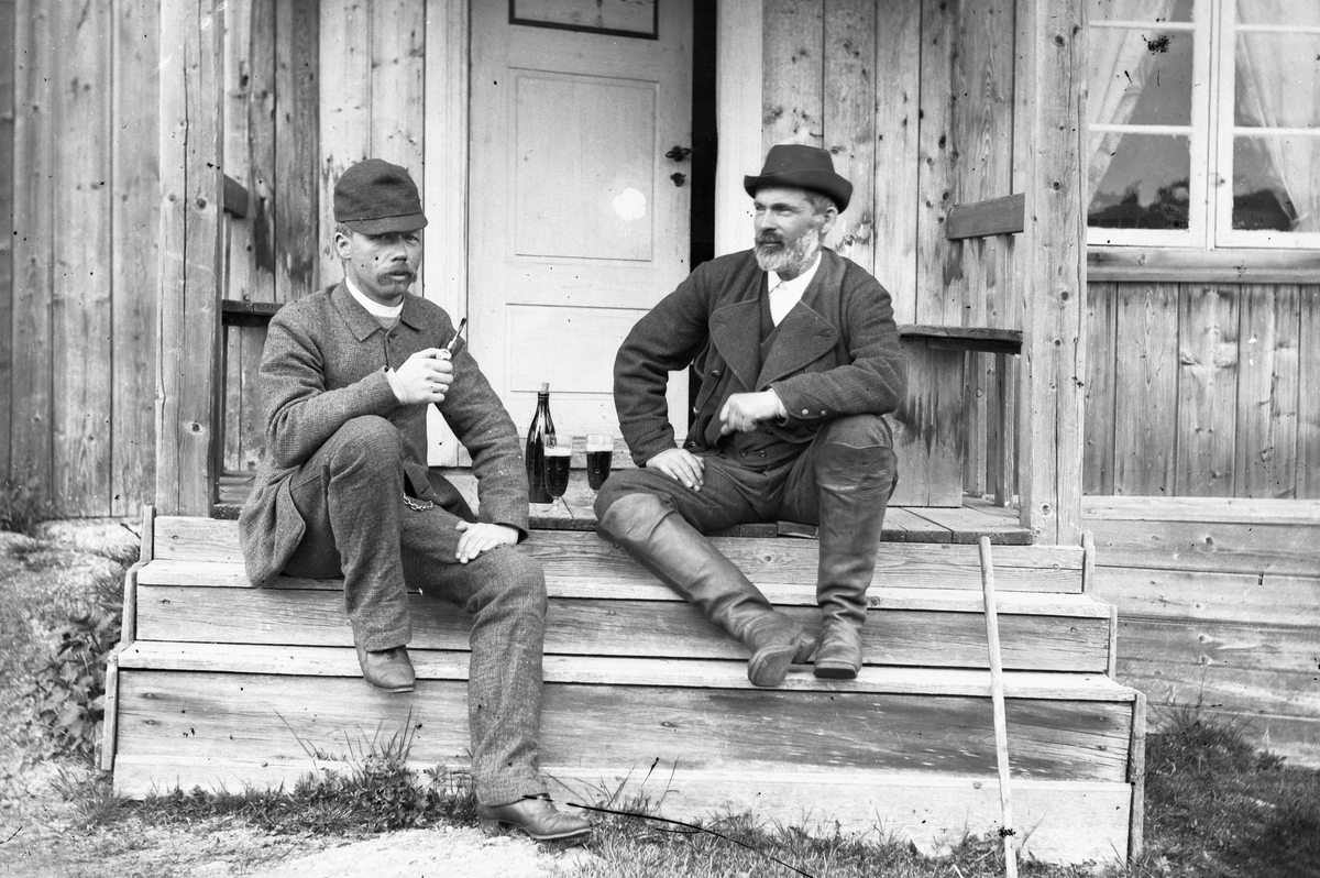Hans Emil Erichsen, 2 menn tar en øl og en pipe på trappa. Kunstneren Ludvik Skramstad til venstre.