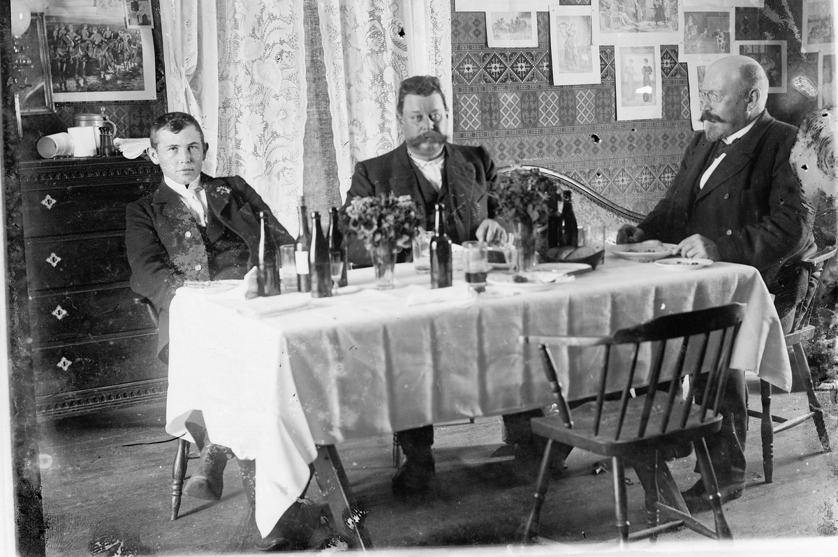 Hans Emil Erichsen, 3 ukjente menn rundt bord. Flasker og glass. Interiør stue.