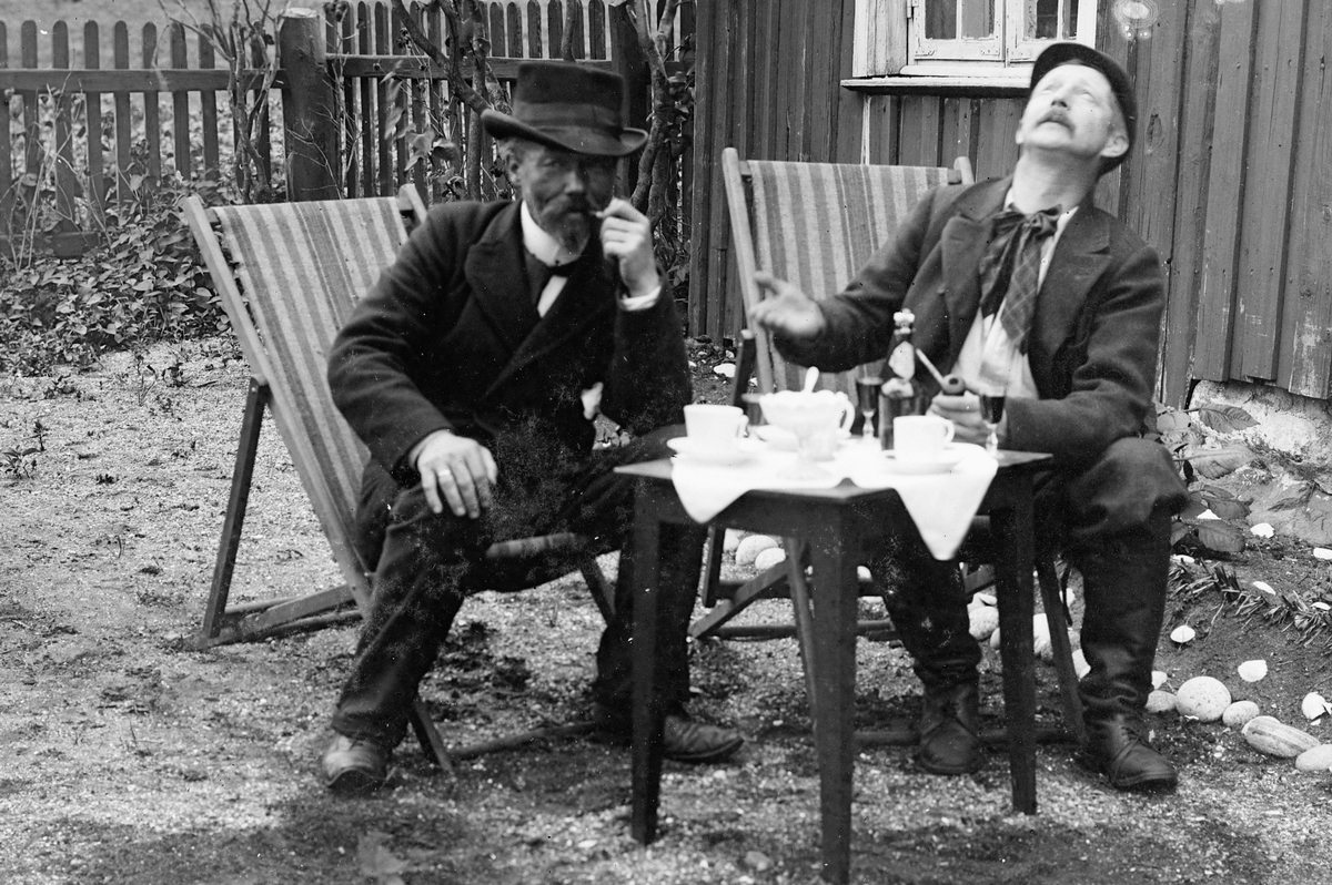 Hans Emil Erichsen, 2 menn ved bord i hagen. Ludvig Skramstad til venstre.