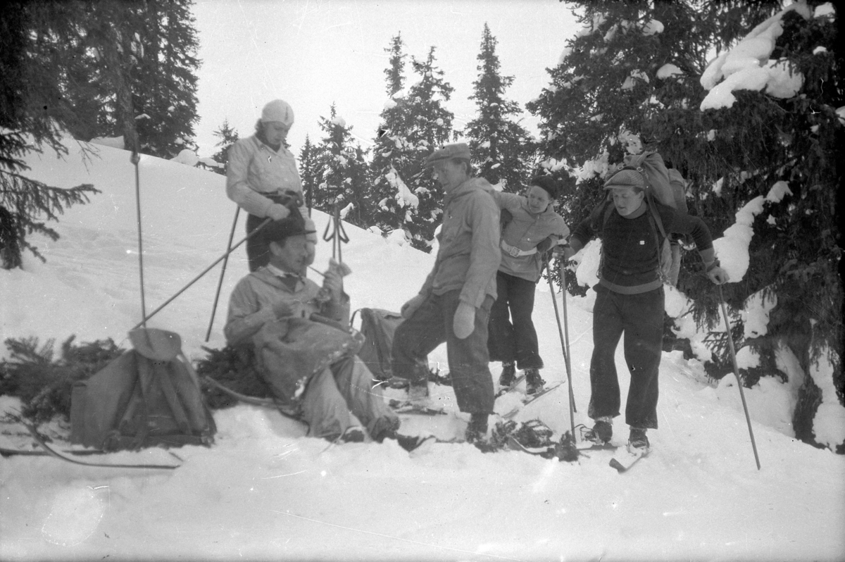 Håkon Prestkværn, Ukjente skiløpere tar en hvil ute i skogen, friluftsliv, skiutstyr, ryggsekker.