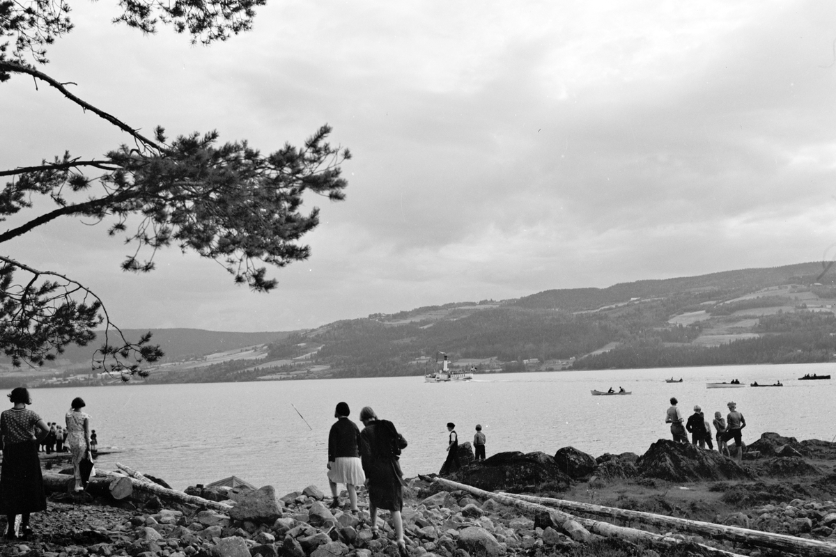 Håkon Prestkværn, Mange mennesker samlet på stranda ved Moelv. Robåter og Skibladner ute på Mjøsa.