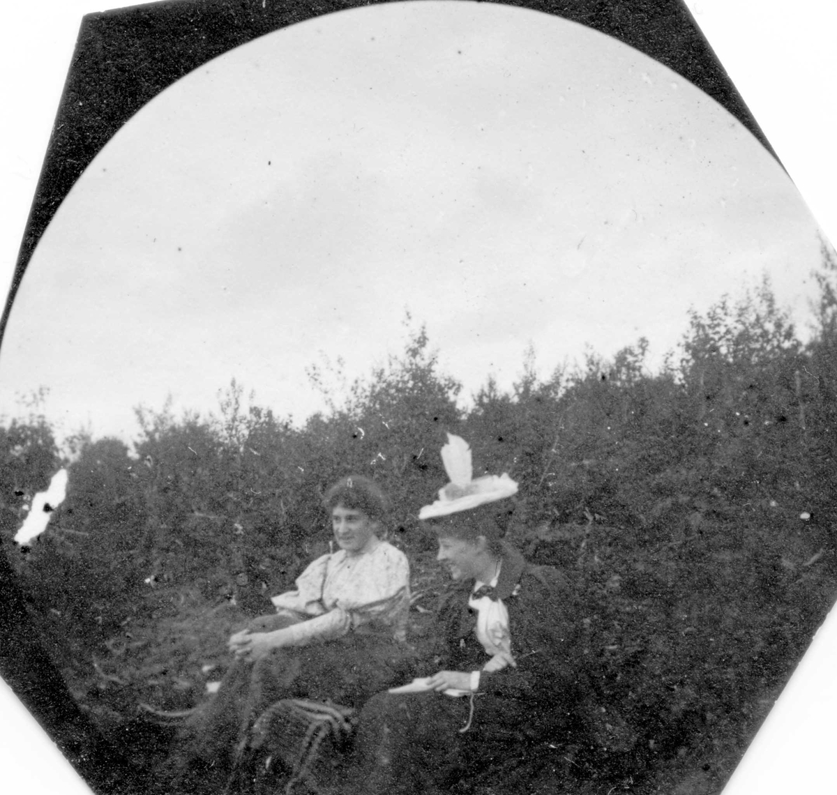 Fredrik Carl Mülertz Størmer, To damer sitter på bakken i skogen, ser bort fra fotografen. En holder hendene rundt knærne.