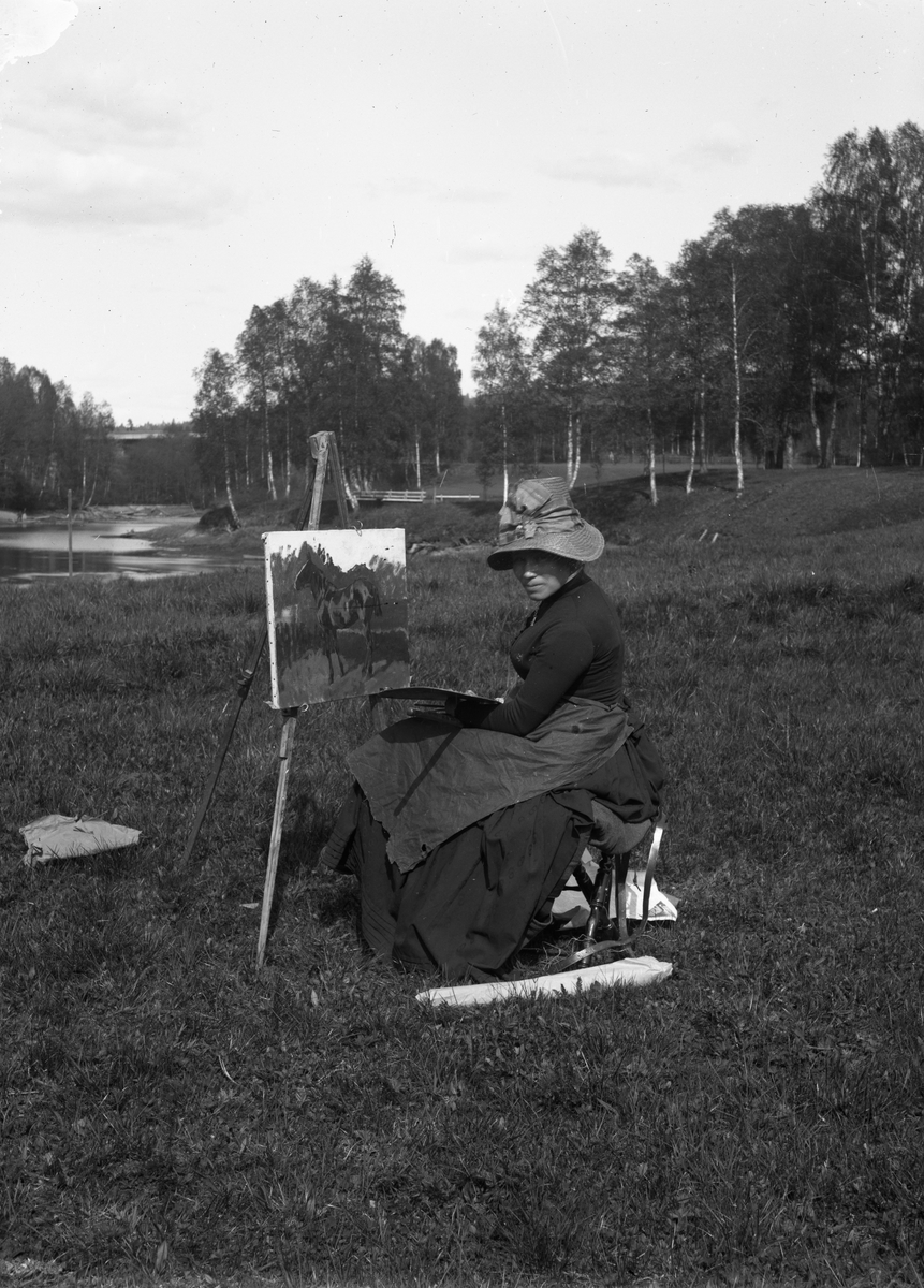 Fredrik Emil Faye, Portrett, malerinne Elisabeth Sinding, sittende med stor hatt utendørs foran staffeli ca. 1885. Fra portrettserie av personer som bodde på eller besøkte Dal gd., Ullensaker, fotografert av gårdens eier, kammerherre Fred. Emil Faye (1844-1903) i årene 1875-1900.