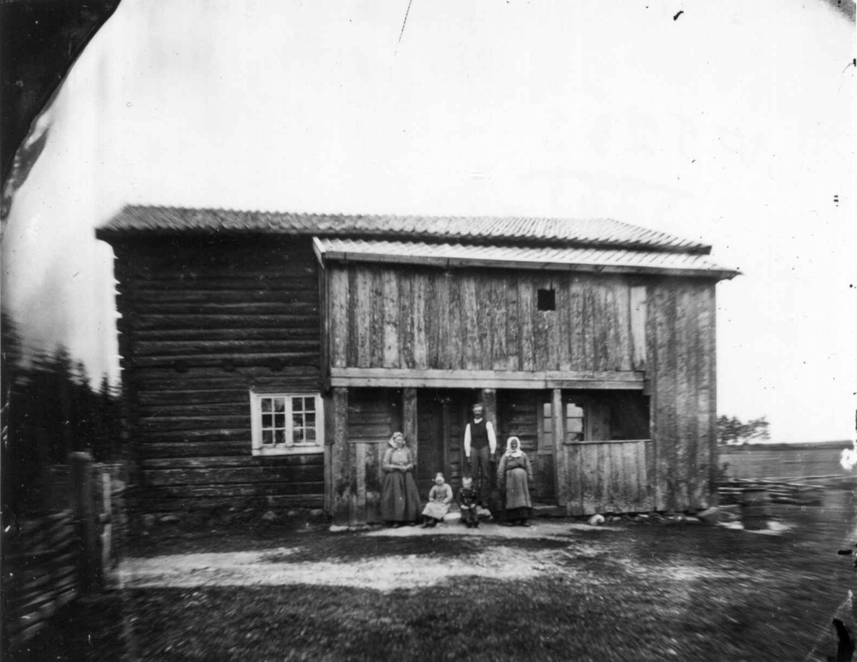 Fredrik Emil Faye, Husmannsfolk (ant.), Ullensaker (ant.). Gruppe poserer foran trebygning. Fra portrettserie av personer som bodde på eller besøkte Dal gård, Ullensaker, fotografert av gårdens eier, kammerherre Fredrik Emil Faye (1844-1903) i årene 1875-1900.