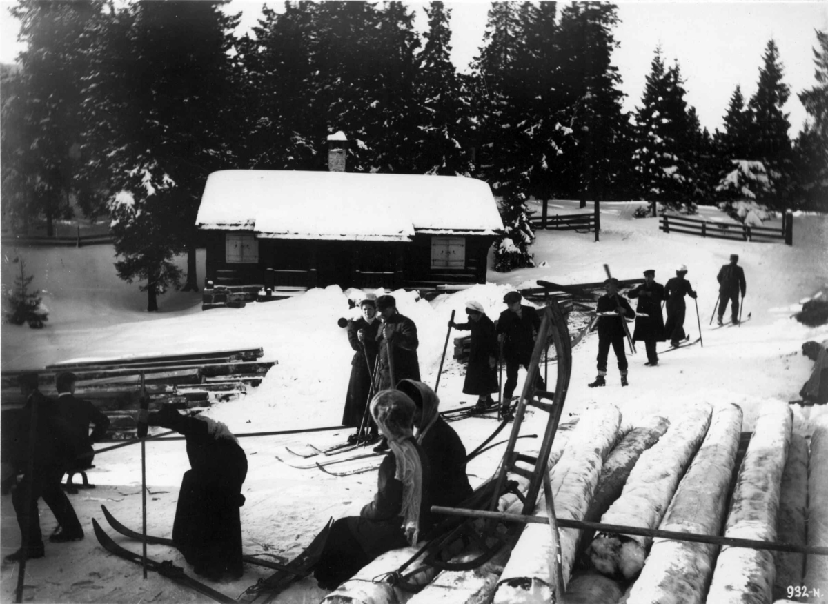 Hermann Christian Neupert, Frognerseteren, Oslo. 1908-1910. Skiløpere og akende. Tømmer. Hytte i bakgrunnen.