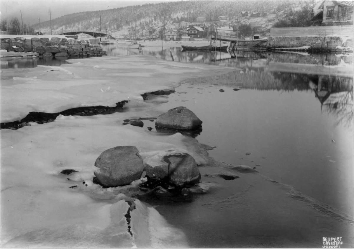 Hermann Christian Neupert, Oslo, Ormøya 1910. Oversiktsbilde. Strandparti. Vinter med is. Bebyggelse. Brygge med båter.