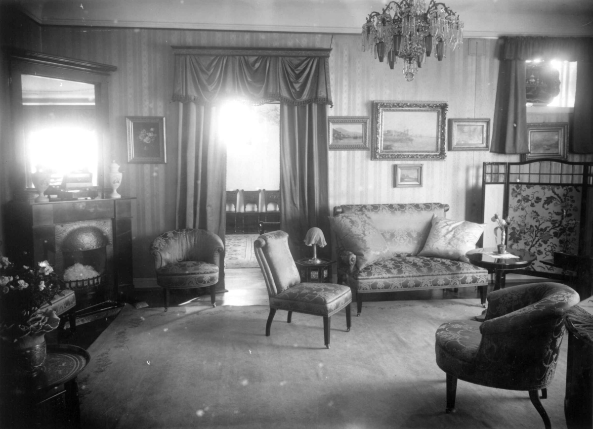 Hermann Christian Neupert, Trapp-Meyer. Stueinteriør. 1925. Sofa. Stoler. Malerier på veggene. Speil. Lysekrone. Kamin. Skjermbrett.