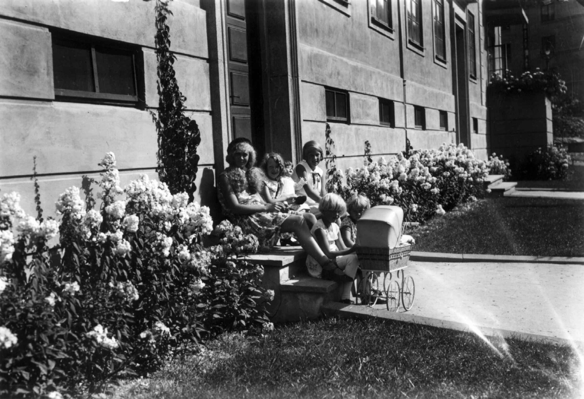 Hermann Christian Neupert, Oslo. 1930. Småjenter med dukker og dukkevogn. Sittende utenfor et hus.