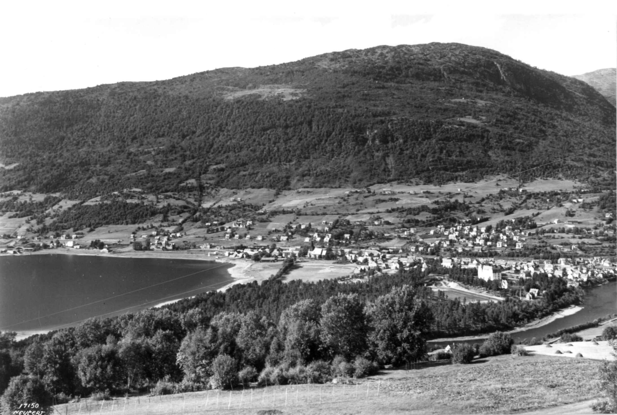 Hermann Christian Neupert, Voss 1939. Oversiktsbilde. Vangsvatnet. Tettbebyggelse omgitt av gårder, åkrer og jorder. Skog og fjell i bakgrunnen.