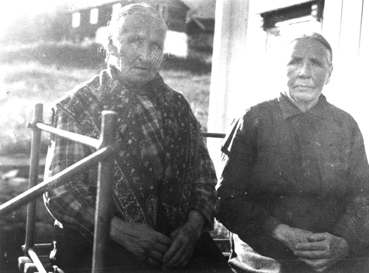 Anna Grostøl, Antagelig Lesja, Oppland 1934. To kvinner sitter utenfor et hus.