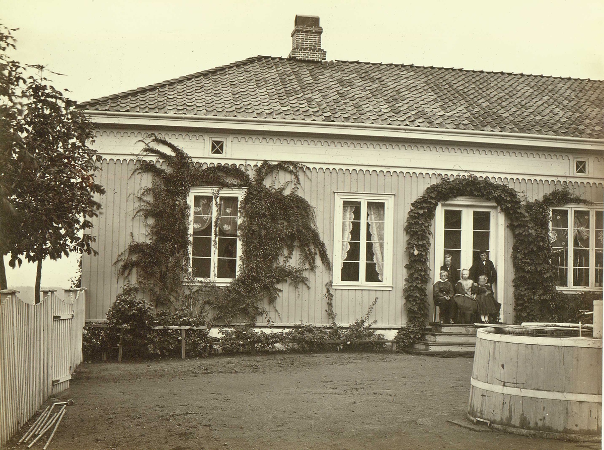 Henry Rosling, Hovedbygning, sannsynlig Lilleby gård, Hokksund, Øvre Eiker, Buskerud. Bildetekst:"Lensmands Barths Hingsund". Eiker hadde en lensmann på 1860-tallet, Anton Barth født ca. 1815, bosatt på gården "Lillebye Haugs Sogn". Persongruppe poserer foran inngangspartiet. Stort lagget kar på gårdsplassen. Fra…