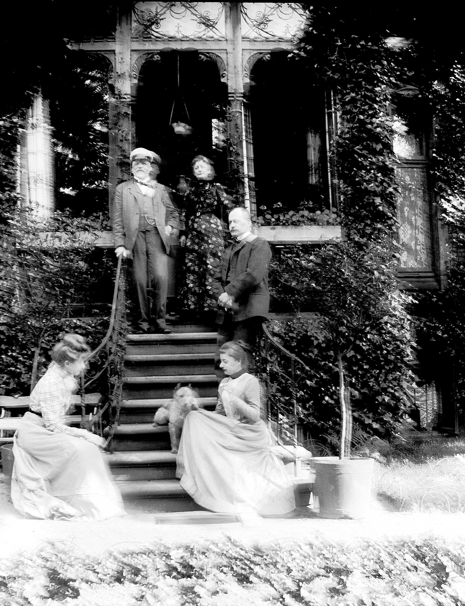 Juliane Fredrikke Langberg, Familiegruppe i trapp foran verandaparti. Sigrid f. Holm (muligens nederst t.v.), fotografens niese, hos sine svigerforeldre (fam. Hudtwalcker) i Blankenese, Hamburg. Øverst fra v. svigerfaren, ant. svigermor, mannen Heinrich (Heini) og nederst t.h. ant. svigerinnen med hund. Meget uskarpt. Fra mal…