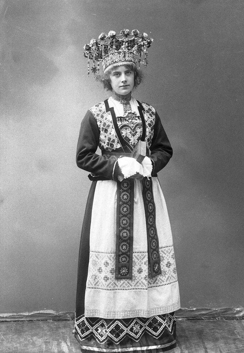 Solveig Lund, Studiofotografi av kvinne med brudedrakt og brudekrone. Holder på salmebok/bibel. Stående. Helfigur. Frontalt vendt. Ser på betrakteren.