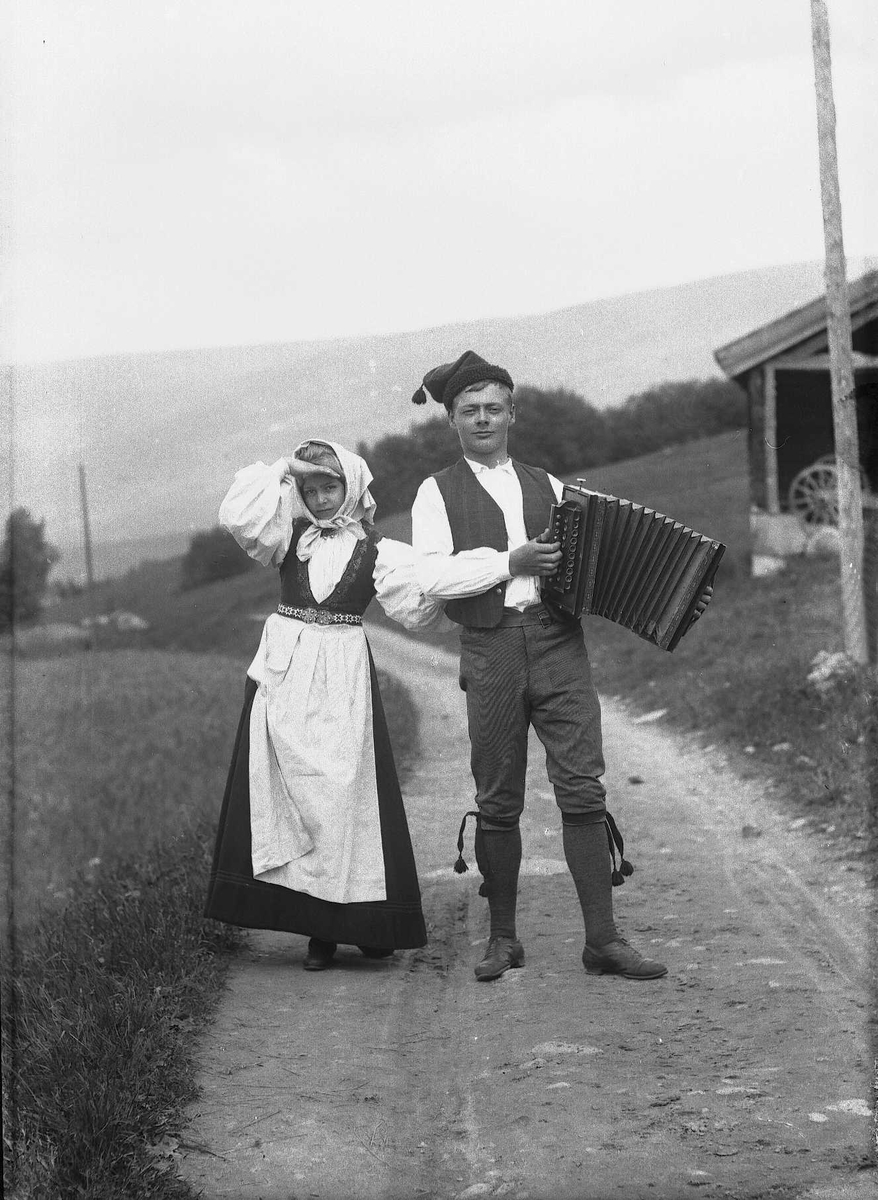 Solveig Lund, Jenta i folkedrakt heter Aagot Hunder og er fotografert sammen med sin bror Caspar Bjerck Hunder ved Hunder gård i Gudbrandsdalen. Bildet er arrangert med klær fra fotografen. Gutten holder et trekkspill.