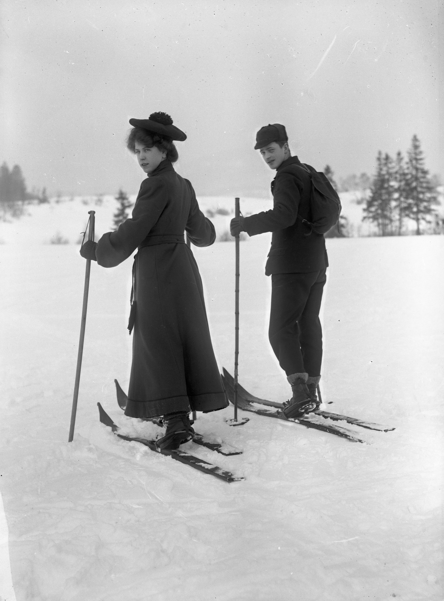 Solveig Lund, Mann og kvinne i snødekt landskap. Fotografert bakfra - begge med ski på beina.