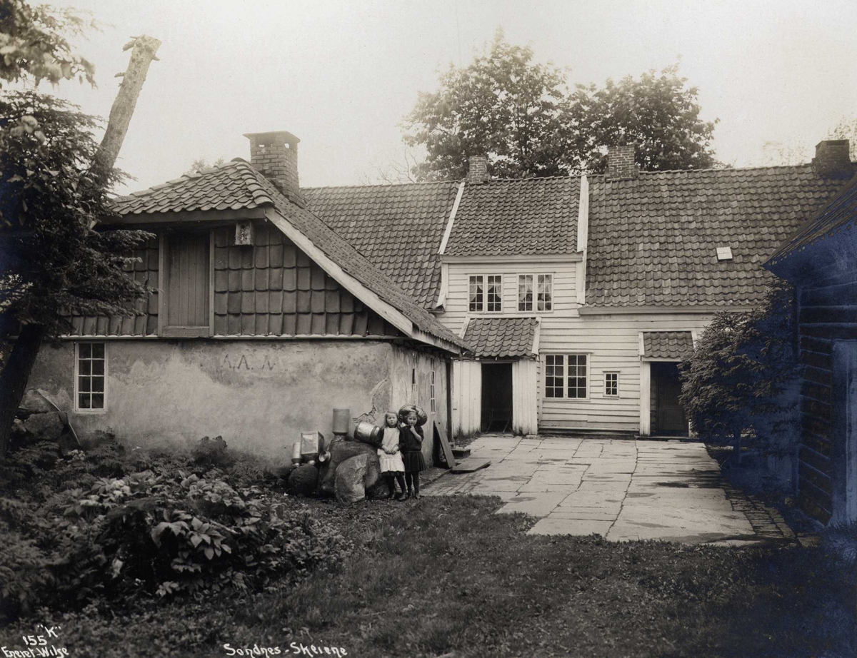 Anders Beer Wilse, Gårdstun, Skeiane gård, Sandnes, Rogaland. To jenter ved uthuset.