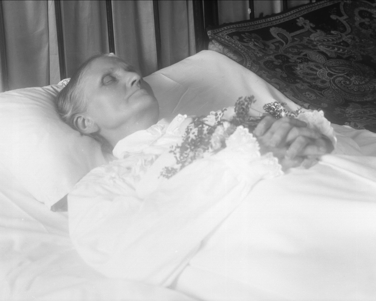 Gustav Borgen, Post mortem-fotografi. Død kvinne i pyntet seng.