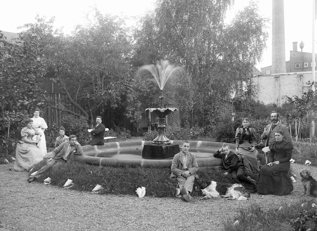 Gustav Borgen, Fra kjøpmann Henriksens landsted. Familien samlet rundt fontene i hagen. Fabrikkpipe i bakgrunnen.