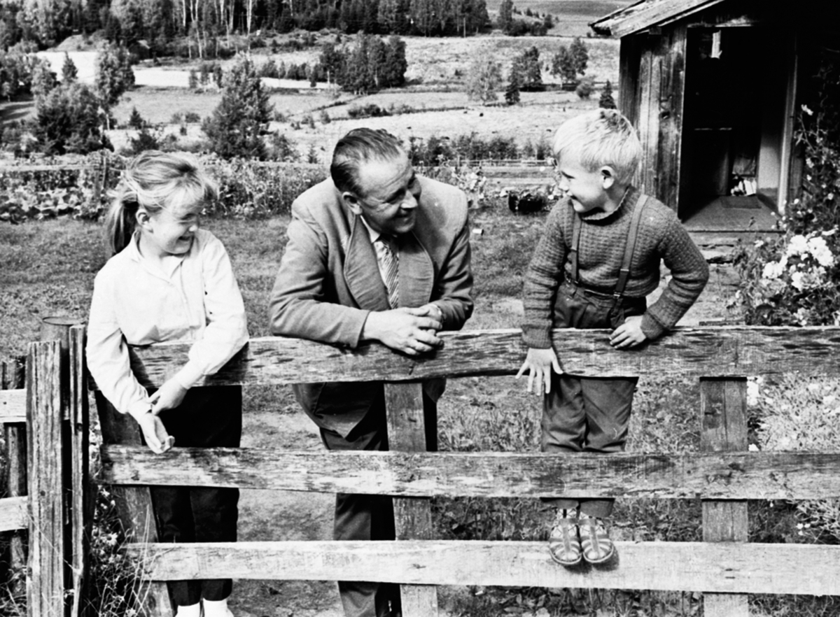 Anno Domkirkeodden, Alf Prøysen med 2 barn ved grinda foran Prøysenstua, Ringsaker. Barna er Mary Kristine og Jan Olaf Hagen. 1961.