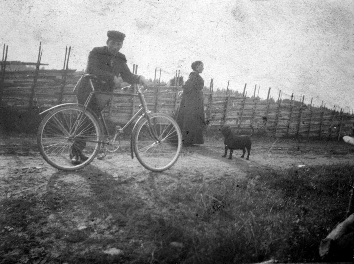 Ukjent, Andreas Arnseth f. 1890-d. 1960, sykkel, ukjent kvinne, hund, skigard, gjerde. Vestre Arnseth 164-1.