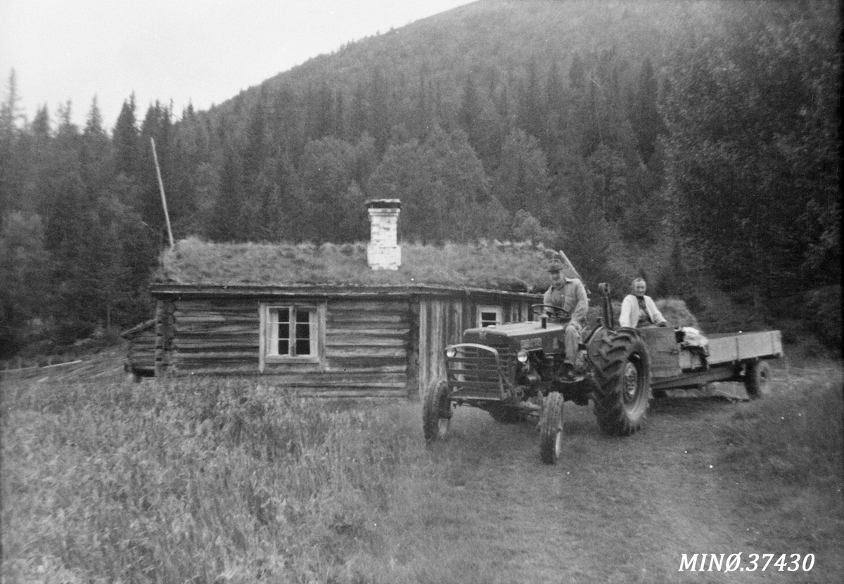 Ukjent, Mann med traktor og tilhenger, kvinne sitter bakpå hengeren