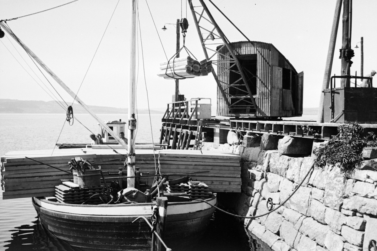 Johs. (Johannes) Johannessen, Jernbanebrygga, Hamar. Bryggekran, lasting/lossing av materialer, planker, mjøsjakt (?) med påbygd styrhus.