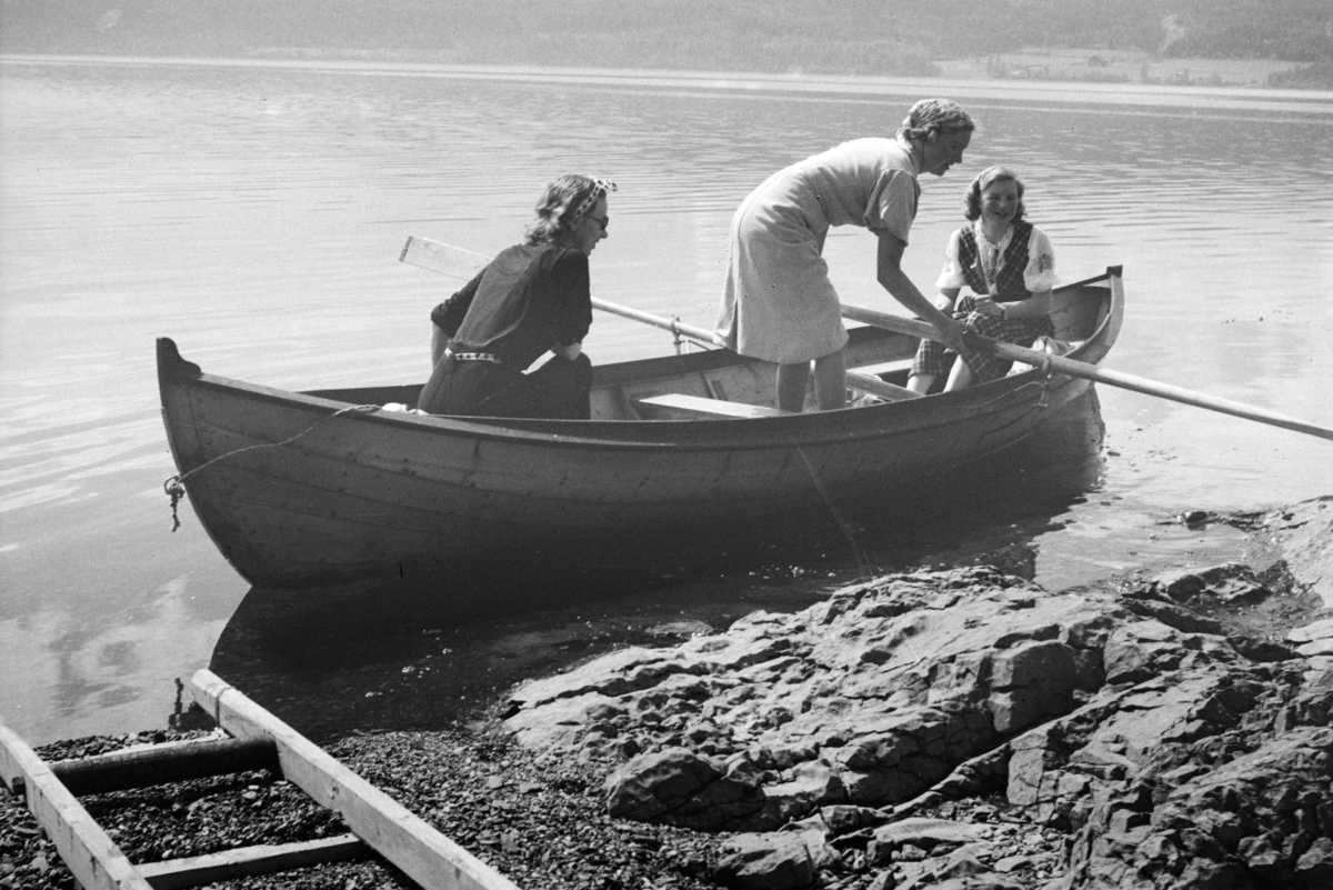 Johs. (Johannes) Johannessen, Lia, Jessnes. Hytta til baker Johs Johannessen. Robåt (dreggebåt, mjøsbåt, Hollandbåt) Mjøsa. Til venstre sitter Lumi Johannessen, to ukjente.