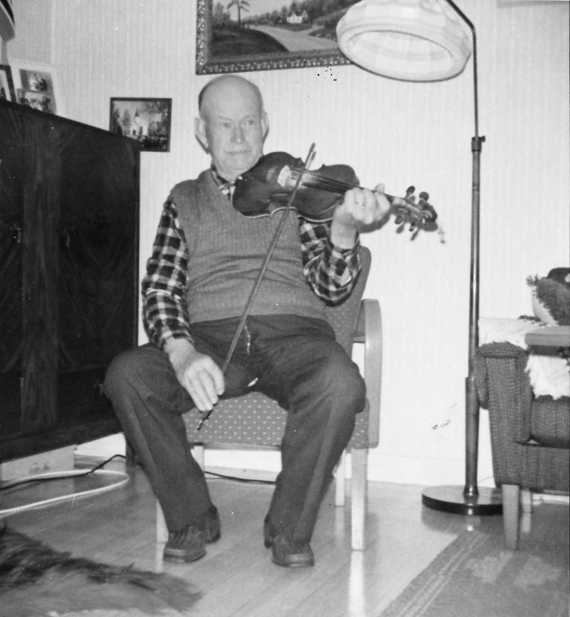 Rachel Haarseth, Mann, klær, fele, stol, lampe, skap.