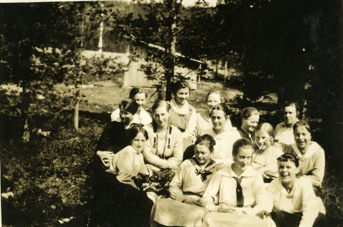 Haakon Garaasen, Vevkurs på Østby. Gruppe på 14 kvinner sitter ute på bakken. 1. rekke fra høyre: nr. 2 Aslaug Nordgaard g. Torgersen (28/8 190 - 1987), nr. 3 Jenny Augustd. Galaasen g. Morud (2/5 1897 - 1979), nr. 4 Bergit Lutnæs (2/7 1901). 2. rekke fra høyre: Kersti Halvorsd. Sætre g. Akre (25/8 1894 - 1978), Ka…