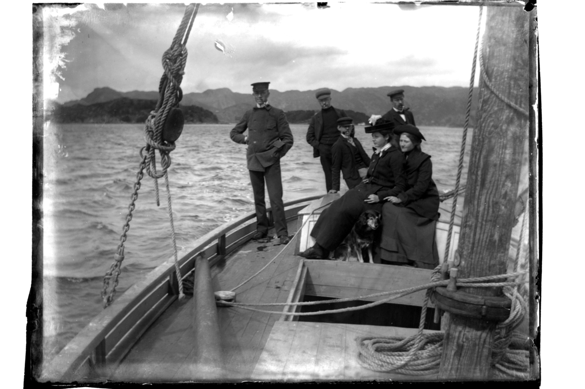 Rolf Sr. Sundt, Fire menn og to kvinner ombord i seilbåt i ukjent farvann. Antagelig fotografert 1903-04.