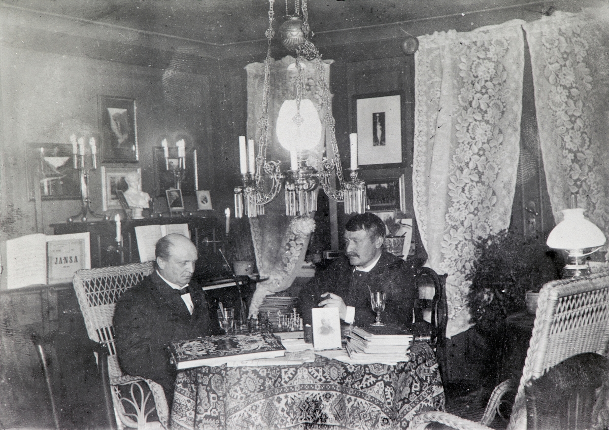 Anno Domkirkeodden, General Christian Wilhelm Engel Bredal Olssøn (1844-1915) og rittmester Jacob Hoel spiller sjakk i stue på Hovelsrud, Helgøya. Interiør stue.