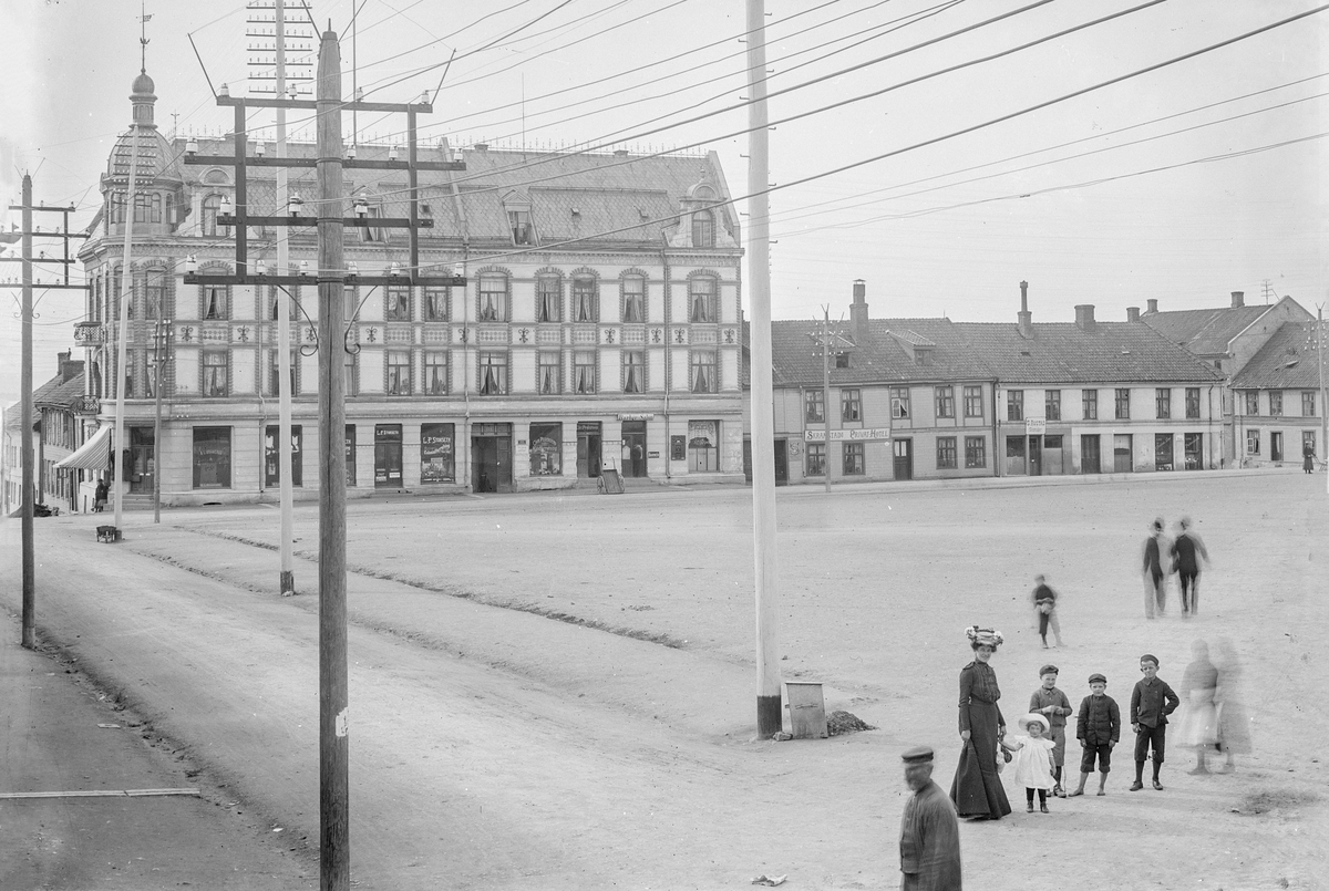 Hans Emil Erichsen, Østre Torg i Hamar. Bebyggelse langs Torggata. Granerudgården med L.P. Storsleth Colonialforretning, Chr. Pedersen Kjødforretning, Skramstad Privathotell, Skomaker S. Rustad. Lysstolper lang Vangsvegen.