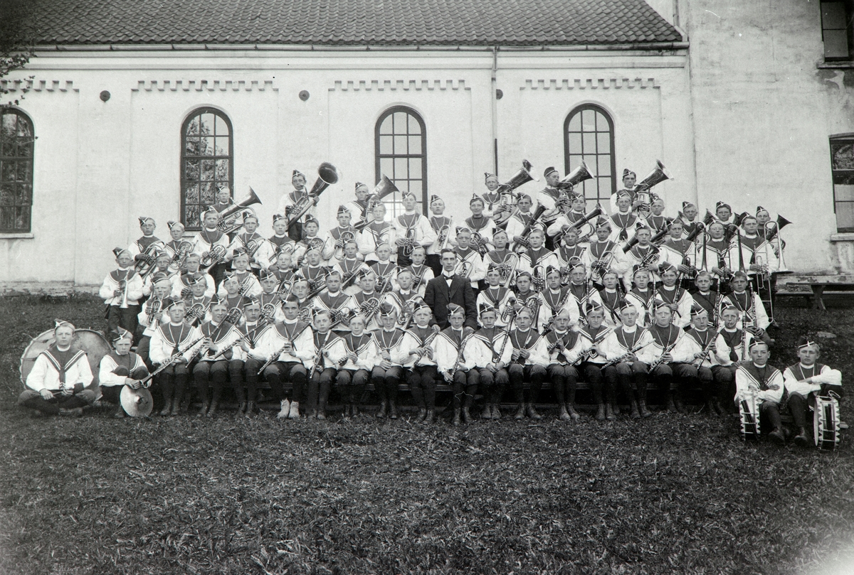 Anno Domkirkeodden, Hamar Guttemusikkorps, gruppe foran Hamar Domkirke, uniformer, instrumenter. 1. rekke f.v. Mikael Kristoffersen, Rolf Morbech, Mikael Sørlund, Walter Lie, Asbjørn Jensen, Einar Kristiansen, Borger Lenth, Johs. Torkildsen, Thorleif Bjølgerud, Oscar Haug, Bjarne Jensen, Jens Holter, Alf Kristiansen, …