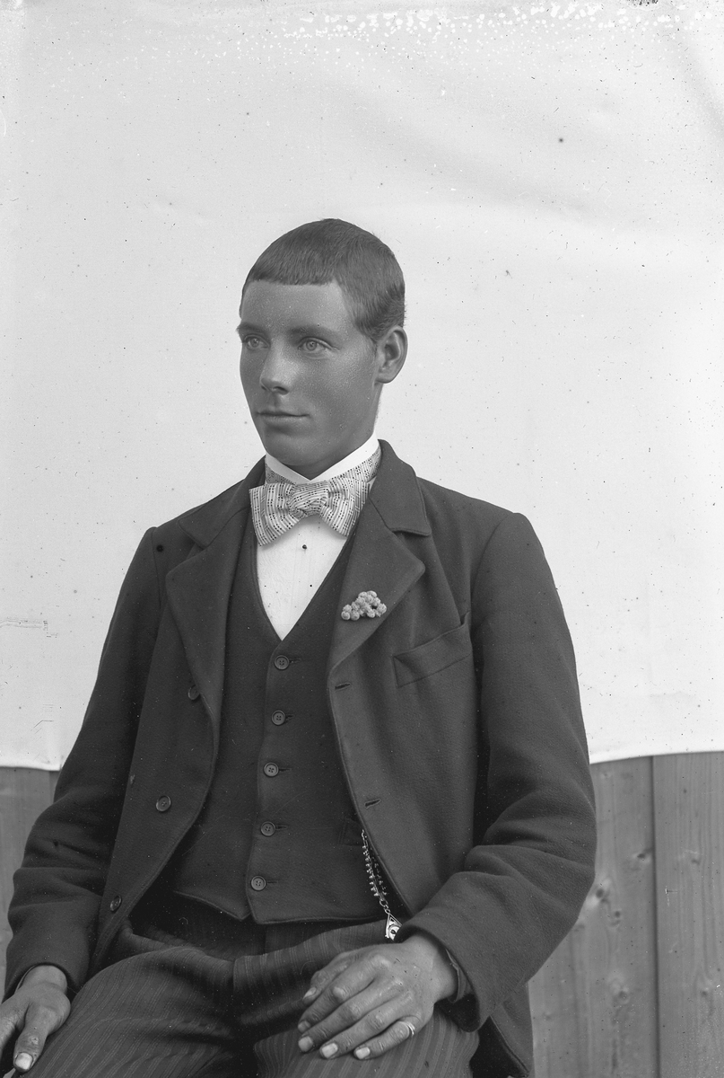 Jakob Jakobsen Engerdal, Ung mann i dress og lys sløyfe, pynt på jakkeslaget, klokkekjede.