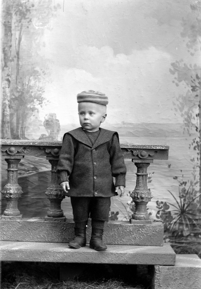 Jakob Jakobsen Engerdal, Liten gutt i dress og lue, står på steinhelle.