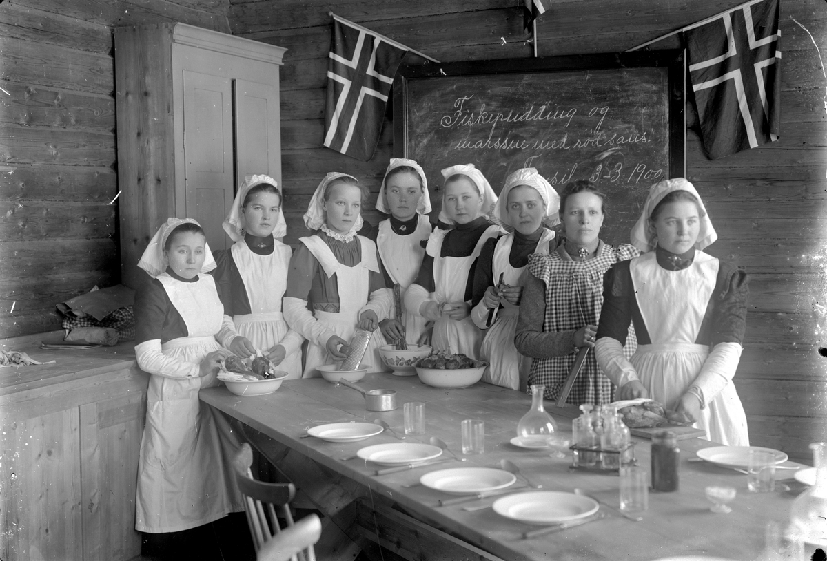 Jakob Jakobsen Engerdal, Åtte jenter på husstellkurs foran tavle der det står "Fiskepudding og marssne med rød saus. Trysil 3 -3 1900".