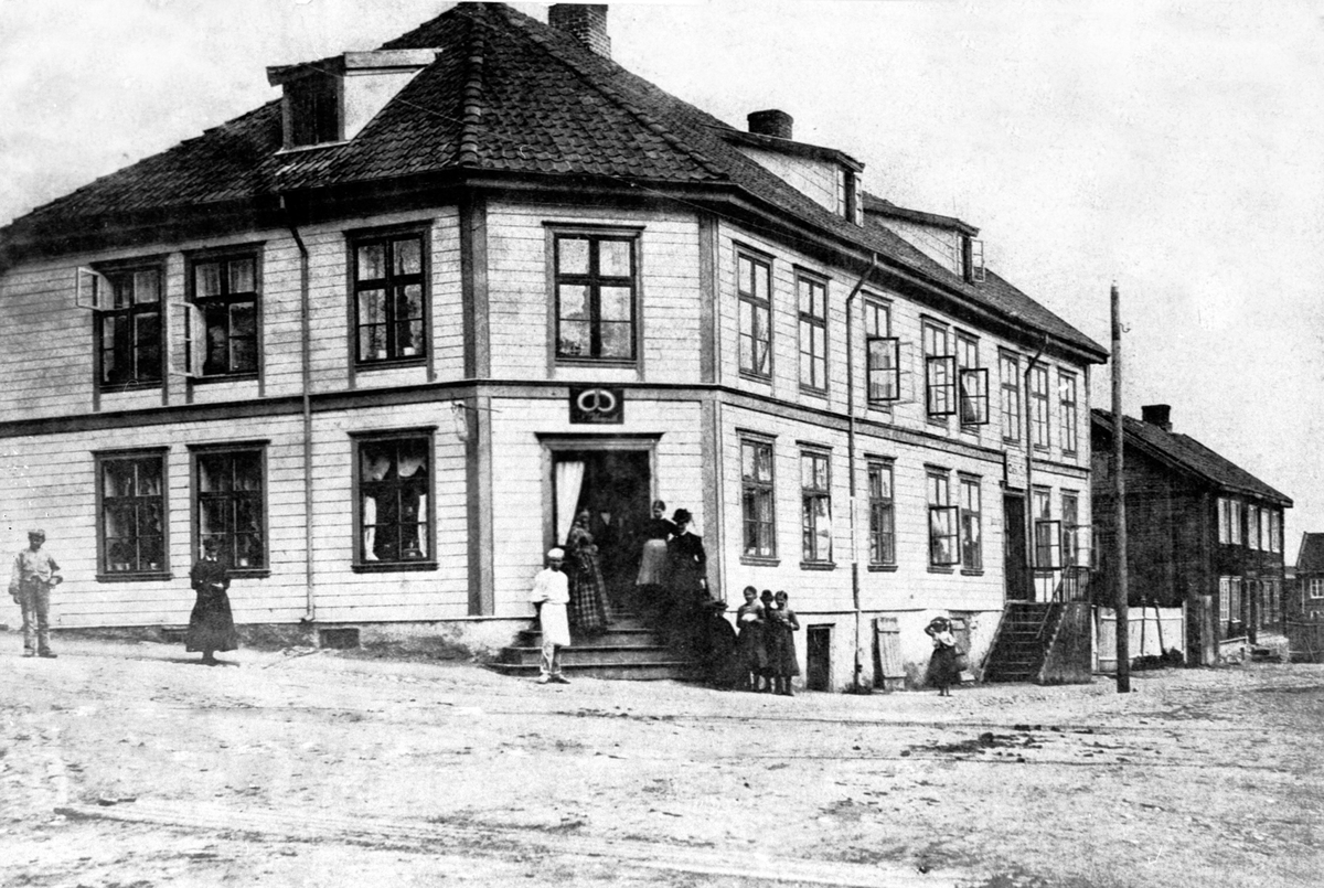 Anno Domkirkeodden, Eksteriør Klungsethgården, Torggata 43, folk foran, bakerskilt. Baker Nils Klungseth i hvitt sammen med betjeningen.