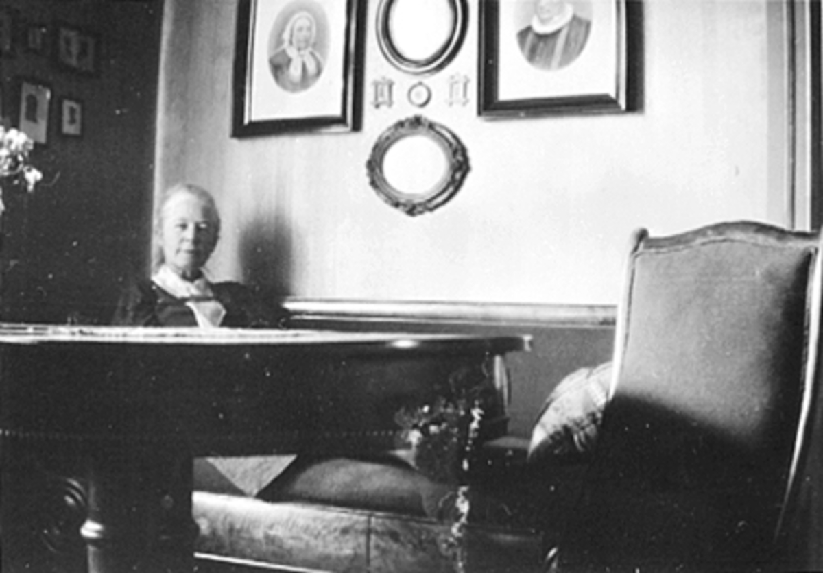 Anno Domkirkeodden, INTERIØR STUE, INGEBORG PETERSEN VED BORDET BILDER AV STABEL PÅ VEGGEN, FAGERVIK, ØSTREGATE 72
