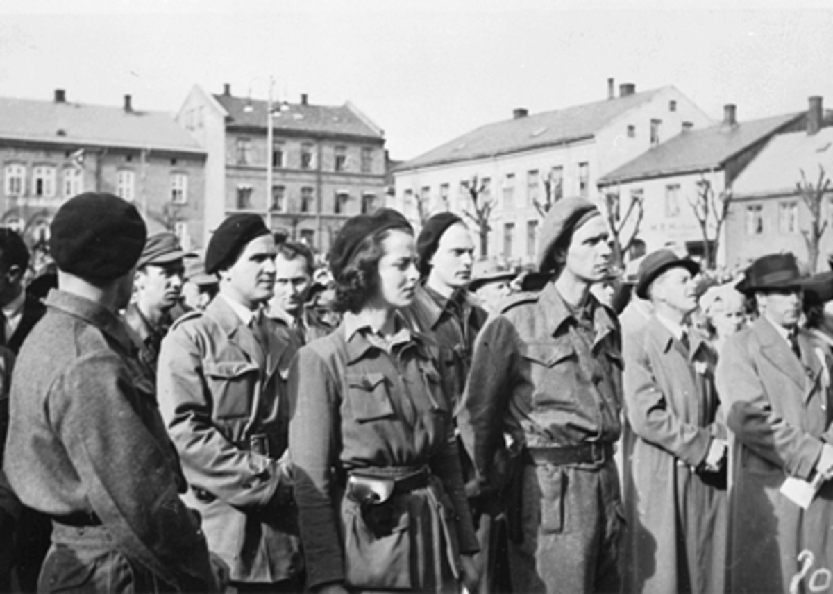 Anno Domkirkeodden, FREDSDAGENE I HAMAR, MAI 1945, SENTRALE HJEMMEFRONTSFOLK PÅ STORTORGET 17. MAI 1945. F. V MED RYGGEN TIL RAGNAR BROCH?, ROLF SUKKESTAD, ANDREAS MURSTAD, ALF BERG, EVA JØRGENSEN, GIFT KLØVSTAD, TOR KLØVSTAD OG KOLBJØRN HENRIKSEN. SE HAMARBOKA 2 S. 187. TEKST BJØRN BÆKKELUND.