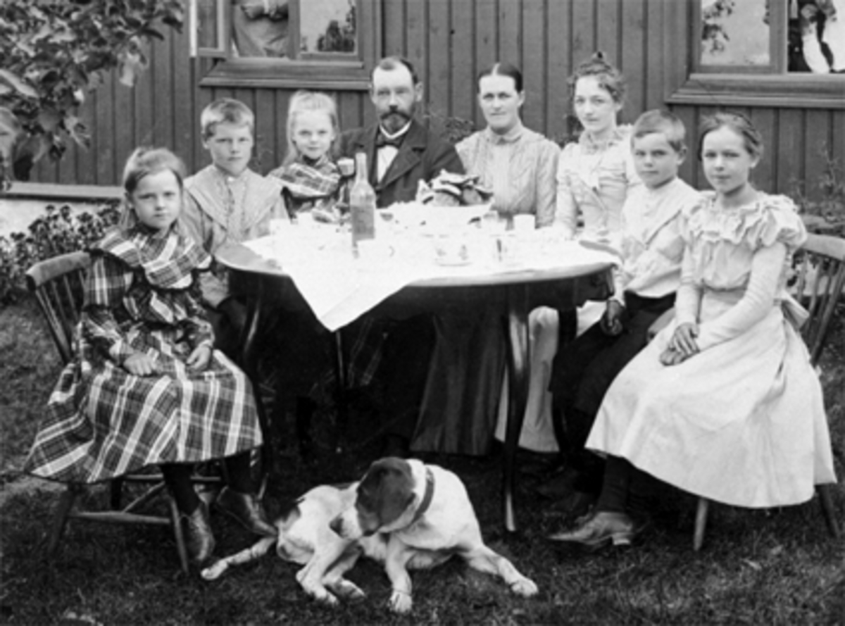 Anno Domkirkeodden, Familien John Kristiansen, bord, hund, landstedet "Bekkesvea". Fra v. Anna, Harald, Nora, John og fru Emma, Signe, Marcus og Marie Kristiansen. Se Hamarboka fra 1982 bilde nr. 258.