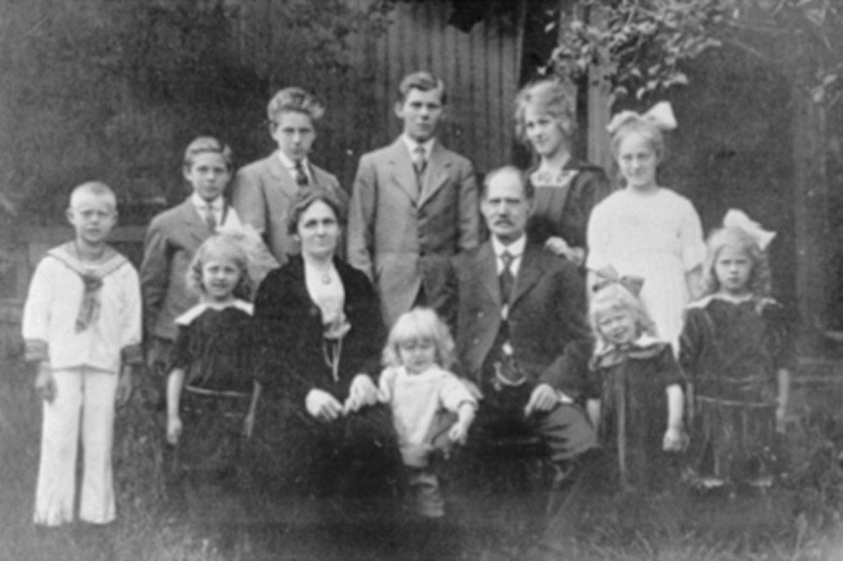 Anno Domkirkeodden, GRUPPE 12, AGNETHE JOHNSEN F:FRØYSLAND, JOHAN JOHNSEN M/BARNBarna fra v: Lina, Arne, Agnes, Martha. Bak fra v: Oscar, Trygve, Olaf, Nils, Johanne, Anna. Se Karin Nord Syverinsens bok Påfuglen i Parken side 113.