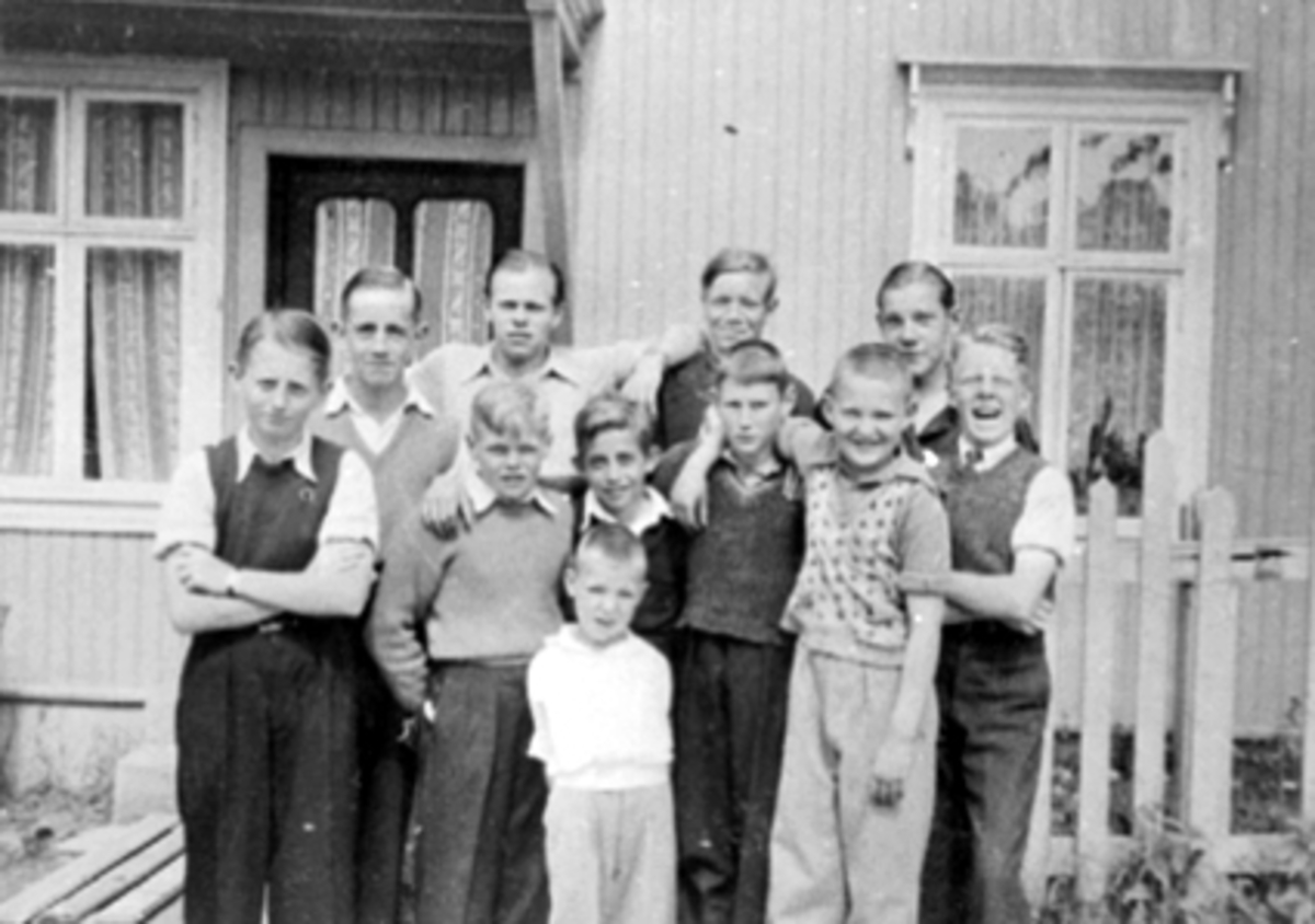 Anno Domkirkeodden, Lars Einar Pedersen, Busse Skaug, Odd Wold, Egil Stensrud, Erling Pedersen, Jonny Nagel, Kåre Johansen. Bak: Rolf Stensrud, Erik Sund, Asbjørn Wold, Arvid Halvorsen. Guttene står foran melkebutikken i Hornsgate, Hamar.